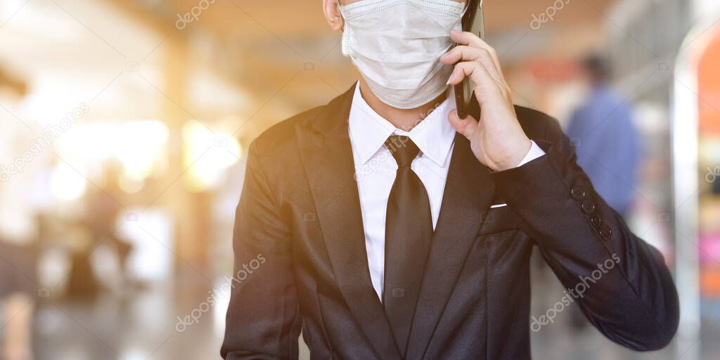 Close-up of businessman wearing face mask in black suit, Using smartphone to talking.