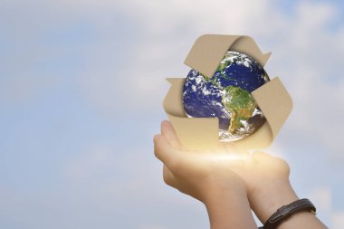 Çevre konsepti. Mavi gökyüzü arkaplanı üzerinde küreler ve geri dönüşüm simgesi olan bir el. Bu görüntünün elementleri NASA tarafından desteklenmektedir