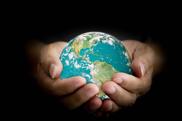 Environment concept. Earth with light in human hand on black background. Elements of this image furnished by NASA