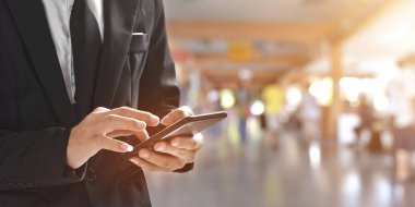 Tren istasyonunda ya da havaalanında akıllı telefon kullanan işadamlarına yaklaş. arama veya sosyal ağlar konsepti.