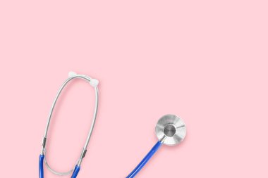 Düz yatıyordu. Pembe arka planda mavi tıbbi steteskop. Aksesuarların sağlık ve sağlık hizmetleri için fikir.