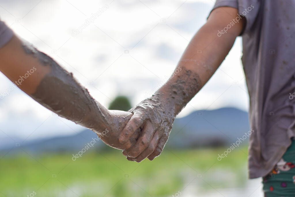 Hands mud clay of two child holding each other. concept of mutual assistance and friendship