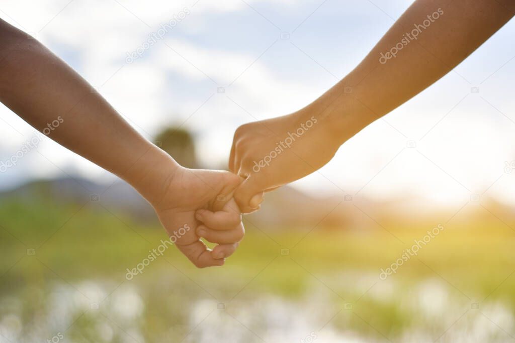 Hands pinkie promise of two child in outdoor. Close up 