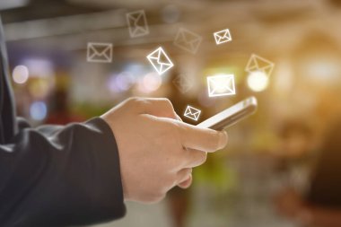 Ekranda e- posta simgesi olan cep telefonu kullanan bir adam el ele tutuşuyor. Ticari iletişim teknolojisi kavramı.