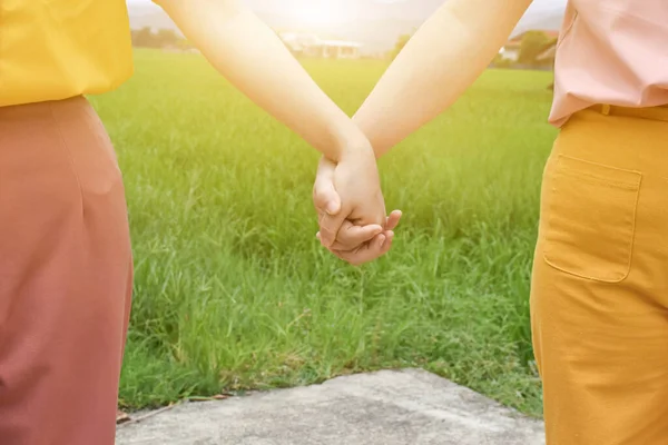 Two female holding hands in nature outdoor.