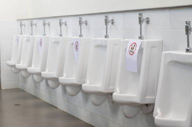 Sosyal uzaklık. Sembollü beyaz pisuarlar umumi tuvalette kullanılmasına izin vermiyor. Enfeksiyonu covid-19 veya coronavirüsten koruma kavramı.