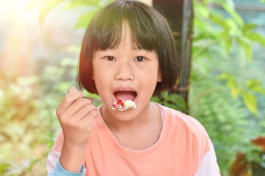 Çocuk kız ellerinin kaşık kaşık dondurma yediği yakın plan. Seçici odak