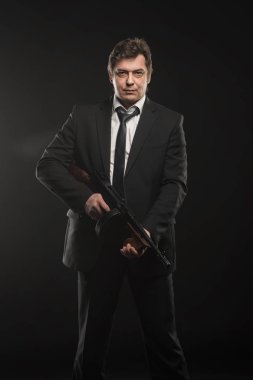 Yakışıklı orta yaşlı adam gangster Thompson makineli tüfek koyu arka plan üzerinde ile