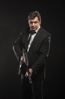 Yakışıklı orta yaşlı adam gangster Thompson makineli tüfek koyu arka plan üzerinde ile