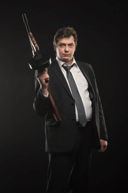 Yakışıklı orta yaşlı adam gangster Thompson makineli tüfek koyu arka plan üzerinde ile