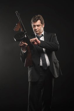Yakışıklı orta yaşlı adam gangster Thompson makineli tüfek koyu arka plan üzerinde ile