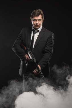 Yakışıklı orta yaşlı adam gangster Thompson makineli tüfek ile sahne duman koyu arka plan üzerinde ile