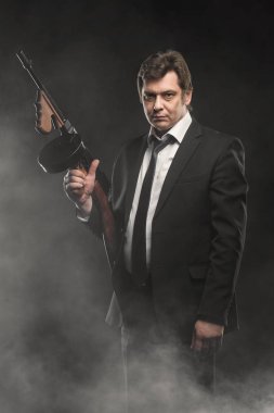 Yakışıklı orta yaşlı adam gangster Thompson makineli tüfek ile sahne duman koyu arka plan üzerinde ile