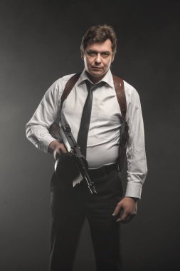 Orta yaşlı dedektif yakışıklı koyu arka plan üzerinde silahla