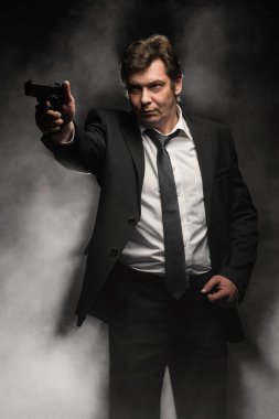 Orta yaşlı dedektif yakışıklı edici top sahne duman ile koyu arka plan