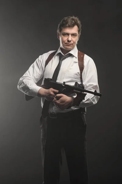 Handsome middle aged detective man with gun on dark background