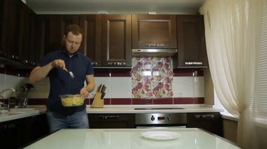 Bir erkek makarna bir tabak içinde koyar.