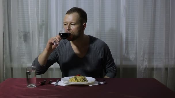 Hombre bebiendo vino y comiendo espaguetis en casa — Vídeo de stock