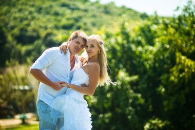 Gelin ve damat açık havada bir güneşli yaz gününde sarılma