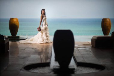 Okyanusun ortasında testiler arka plan üzerinde lüks beyaz bir elbise içinde gelin standları