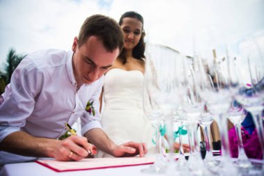 Damat evlilik kayıt belgeleri imzalar. Genç bir çift düğün belgeleri imzalar. Açık Hava düğün töreni