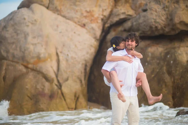 Sposa Siede Sulla Schiena Dello Sposo Contro Rocce Acqua Mare — Foto Stock