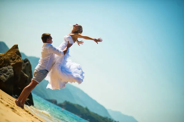 在阳光明媚的夏日 新郎在海边的海滩上跳跃着追赶新娘 — 图库照片