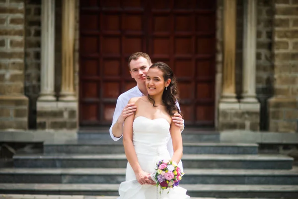 Noivo Roupas Brancas Abraça Noiva Contra Pano Fundo Igreja Católica — Fotografia de Stock