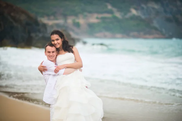 the groom is holding the bride by the sea. couple in love on a deserted beach