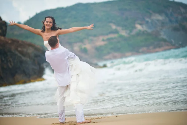 the groom lifted the bride, which spread hand in hand. couple in love on a deserted beach by the sea