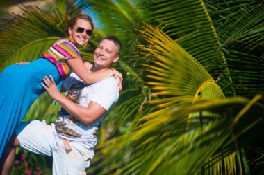 Genç adam ve kadın palmiye ağaçları karşı poz