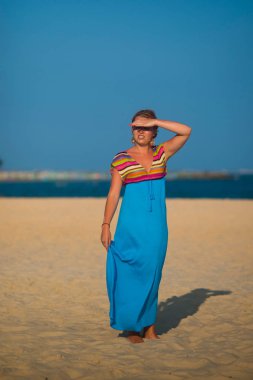 Okyanusa karşı sahilde duran mavi elbiseli kız