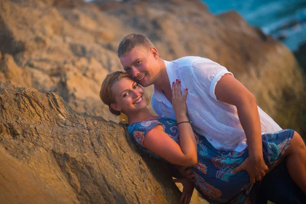 Άνδρας Και Γυναίκα Αγκαλιάζει Βράχια Στο Ηλιοβασίλεμα Ενάντια Στον Ωκεανό — Φωτογραφία Αρχείου