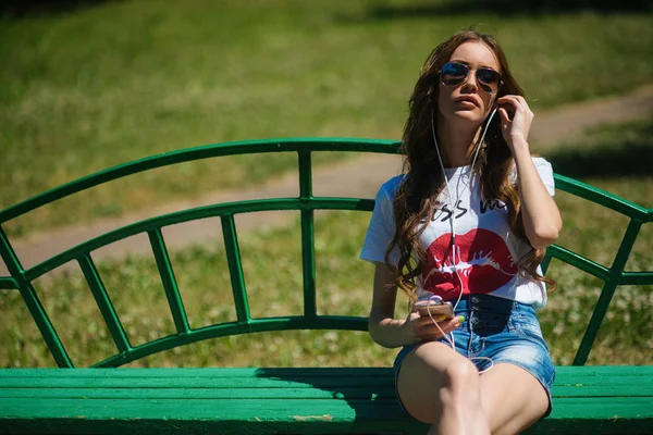 Krásná Mladá Dívka Poslechu Hudby Sluchátkách Sedí Lavičce Parku — Stock fotografie