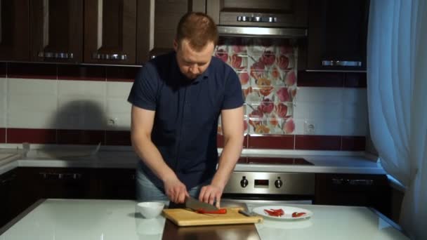 Rode chilipeper snijden. Een man snijdt peper op een houten plank — Stockvideo