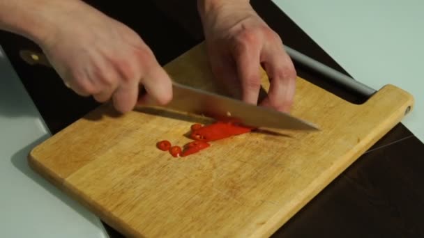 Affettare peperoncino rosso. Un uomo taglia il pepe su una tavola di legno — Video Stock