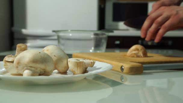 Чоловічі кухарські руки, що ріжуть свіжі гриби на дерев'яній дошці — стокове відео