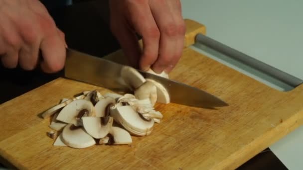 Нарізання грибів на дерев'яній дошці. Чоловік ріже гриби — стокове відео
