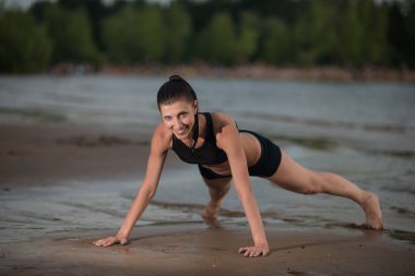 Sevimli kadın şınav denize karşı sahilde günbatımı