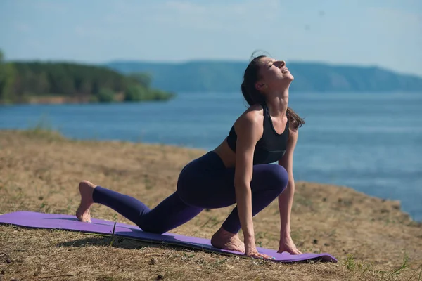 Young woman doing yoga on the background of the sea