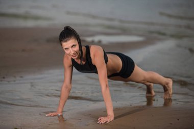 Sevimli kadın şınav denize karşı sahilde günbatımı