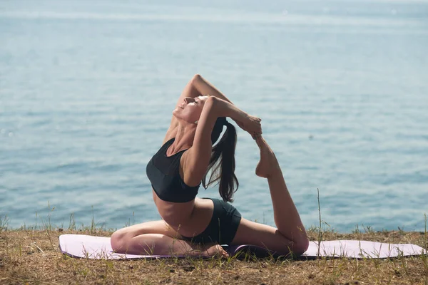 Young woman doing yoga on the background of the sea