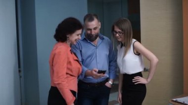 İş arkadaşları Smartphone videoyu izleyin ve ekrana işaret şaşırttı