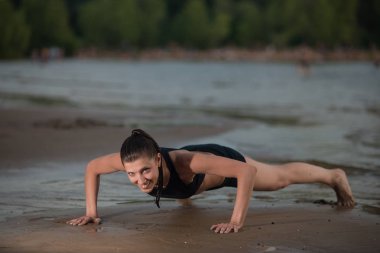 Sevimli kadın şınav denize karşı sahilde günbatımı