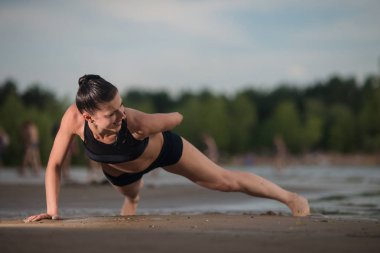 Sevimli kadın şınav denize karşı sahilde günbatımı