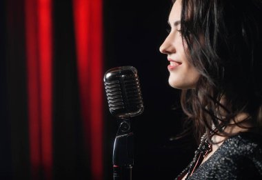 Kırmızı ve siyah arka plan üzerinde mikrofon şarkı güzel kadın portresi