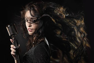 Bir mikrofon ve çırpınan saçlı güzel bir şarkıcı portresi