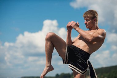 Genç bir savaşçı tekme. Açık havada egzersiz. Diz tekme