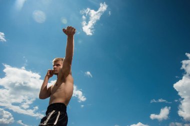Kaslı erkek savaşçı gökyüzü artalanları üzerinde eğitim. Açık havada boksör trenler
