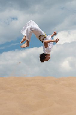 Acrobat akrobatik bir hüner, takla sahilde gerçekleştirir. Adam trenler capoeira